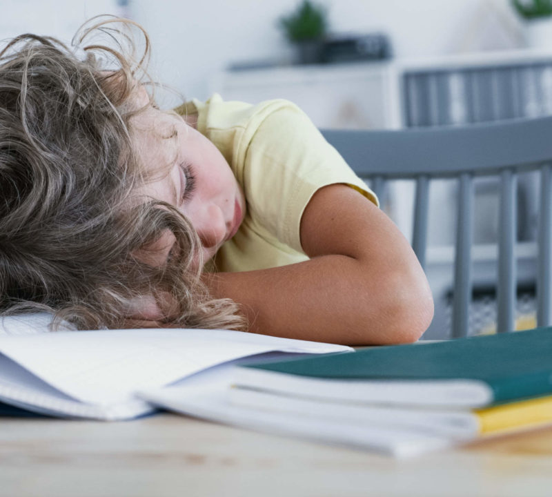 close-up-of-a-tired-kid-sleeping-with-his-head-res-VE6TYD7