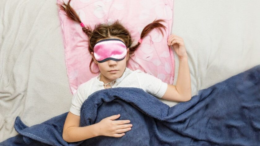 high-grade children's sleep. child girl in a sleep mask sleeps in a bed in a room