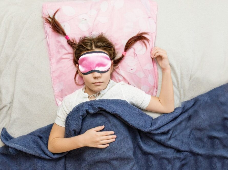 high-grade children's sleep. child girl in a sleep mask sleeps in a bed in a room
