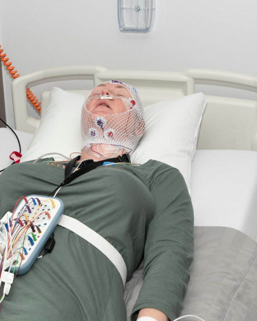 Middle aged woman measuring brain waves, examining polysomnography in sleep lab